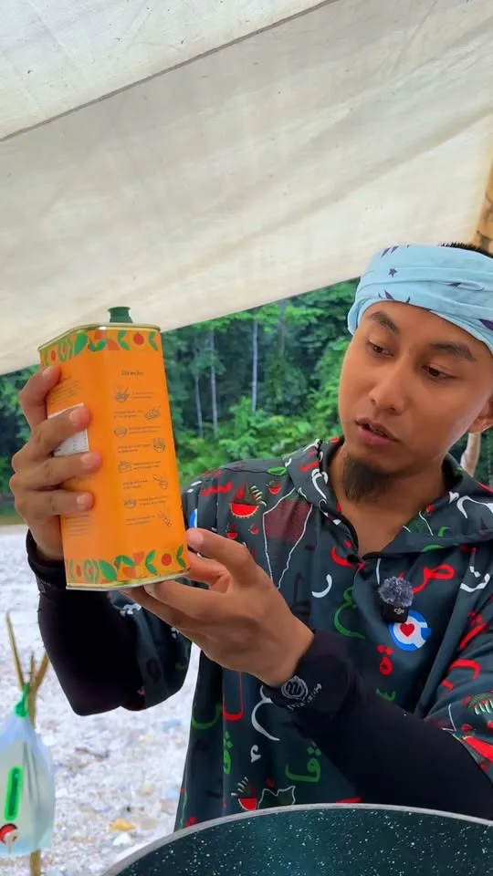 Abe Wea di bawah khemah dalam hutan membaca tin minyak zaitun Sihaté