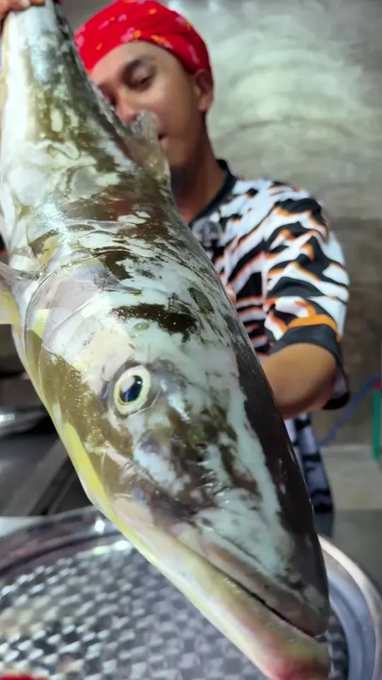 Abe Wea memegang ikan haruan tasik besar di dapur