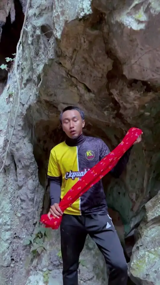 Abe Wea di mulut gua batu menunjukkan kain lepas merah berbunga