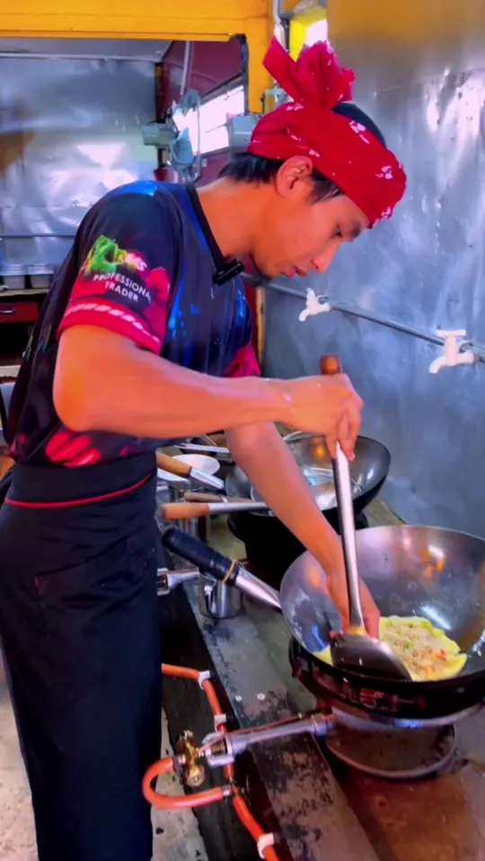 Abe Wea memasak nasi goreng pataya dalam kuali di dapur