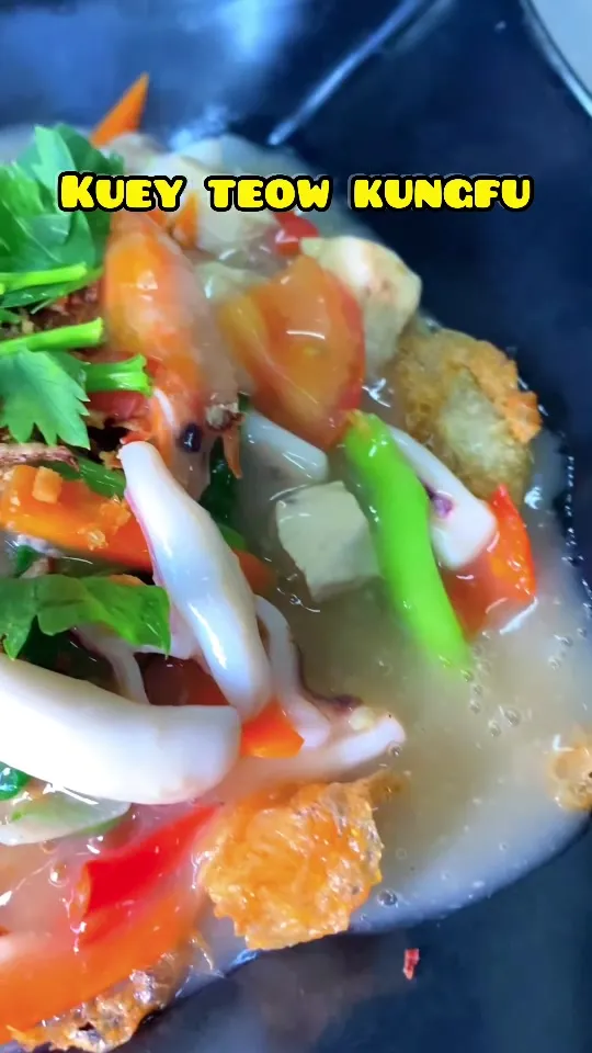 Kuey teow kungfu dengan sotong, tomato dan cili dalam kuah pekat, dengan tulisan Kuey teow kungfu
