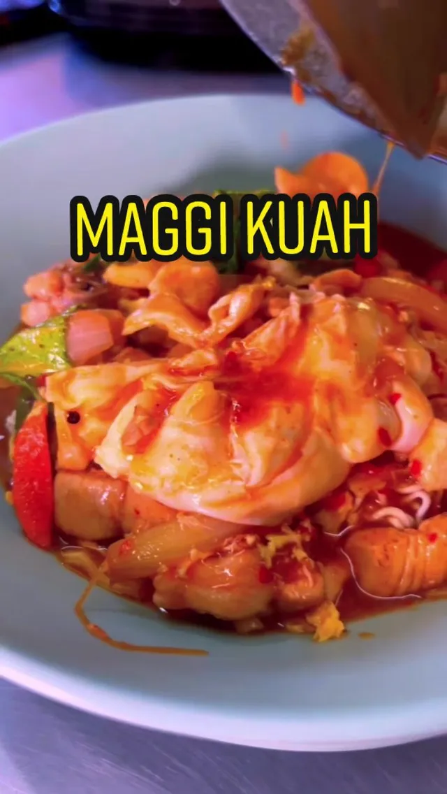 Semangkuk maggi kuah dengan telur, sayur dan makanan laut, dengan tulisan MAGGI KUAH