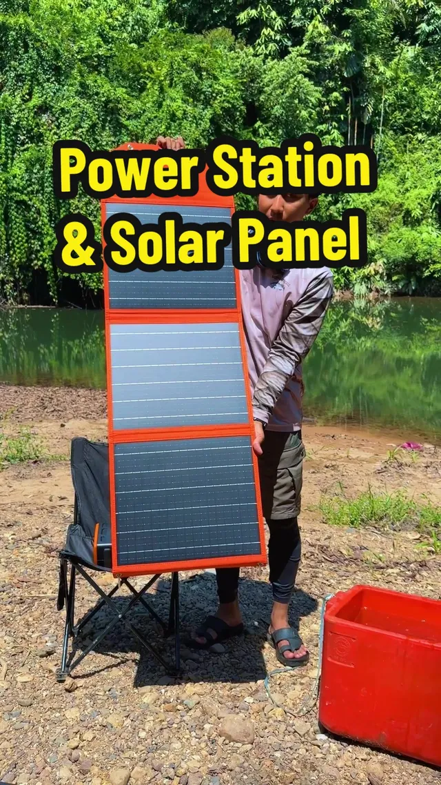 Panel solar lipat diangkat di sebelah kerusi camping di tebing sungai