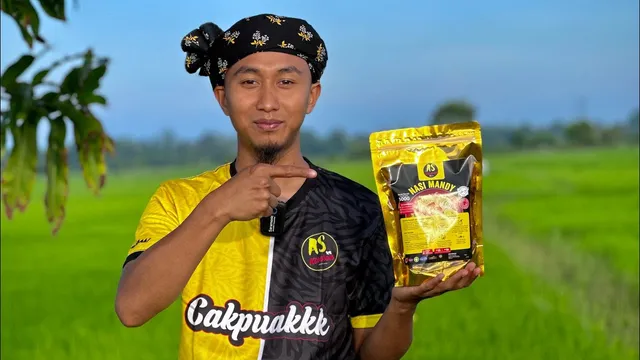 Abe Wea di sawah padi memegang pek Nasi Mandy AS Kitchen