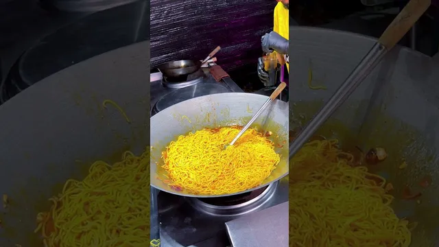 Mee goreng kuning dalam kuali besar di atas dapur gas