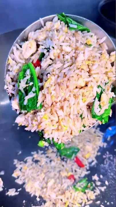 Senduk penuh nasi goreng dengan sayur dan cili